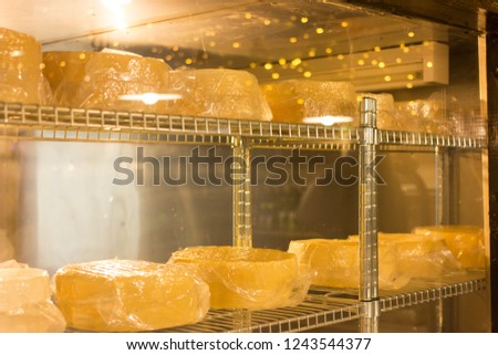 Metal rack with young cheese in a vacuum pack. Aging chamber