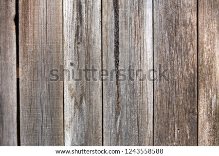 Close-up of natural old vintage weathered gray brown unpainted solid wooden fence or gate of planks and boards. Ecological texture vertical copy space sunny crackled background.