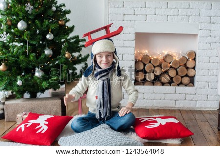 New Year's photo of a boy in a hat with a toy in his hands and a smile on his face