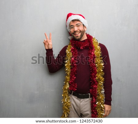 Young man celebrating christmas day holding gifts doing a gesture of victory