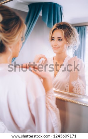 Beautiful girl in a bathrobe in the morning admires herself in the mirror