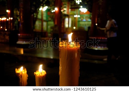 A row of big candles lighting in the dark night with blurred a Chinese shrine 