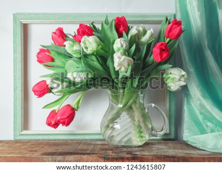 Classic still life with red and white tulips on the background of green empty picture frame and greed drapery