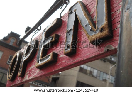 old, weathered, wooden, red and black "Open" sign on storefront in the city