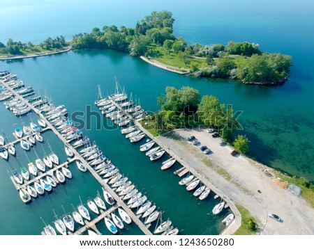 Aerial picture of marina a dock with yachts and boats, motorboats and vessels floating on water in dock.