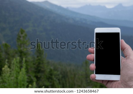 Smart phone in travelers hand in the mountains.The use of the smartphone in the highlands. 