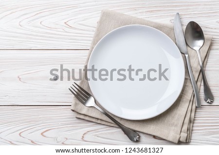 empty plate spoon fork and knife on table Royalty-Free Stock Photo #1243681327