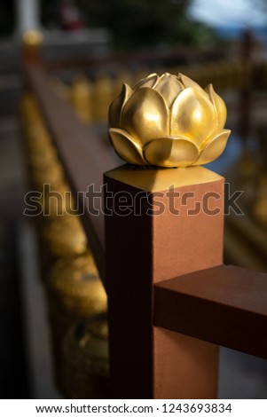 Close up on a dark gold lotus ornamental carving on a Buddhist prayer alter, with space for text on the bottom