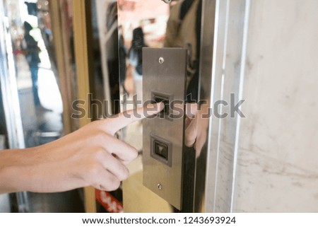 Close up man hand press a up button of elevator inside the building for upper high level floor.