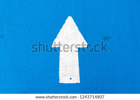 White painting in forward direction arrow symbol on blue concrete road background