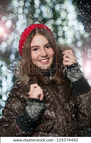 Fashionable Teenage Girl Wearing Cap And muffler Coat In Studio With Snow.Portrait of young beautiful girl in winter style.bright picture of beautiful teen girl in hat, muffler and mittens