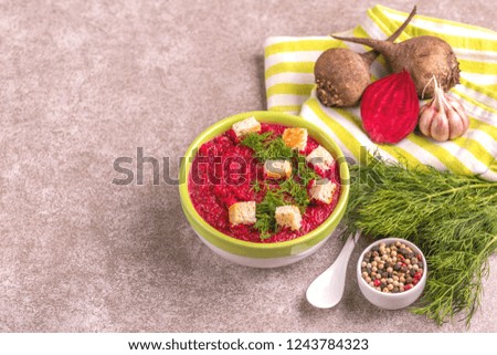 Bright tasty pureed beetroot soup in clay bowl with ingredients. Healthy food concept. Gray marble background. Horizontal view. Copy space