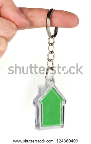 Keychain with figure of green house. Hand holding key and Keychain.