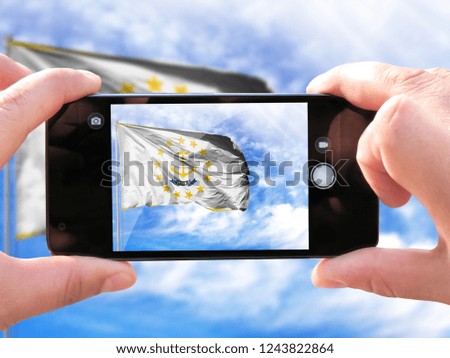 The hands of men make a phone photograph of the flag State of Rhode Island and Providence Plantations .