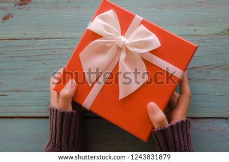 Top view of hands with red gift box on vintage wooden,this image for happy brithday and happy birthday or happy new year.