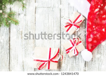 Christmas holiday wooden background with fir branches, Santa hat and gift boxes decorated with snow. top view, copy space