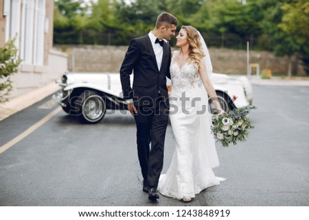 Beautiful bride in a long white dress. Handsome groom in a black suit. Couple near old car