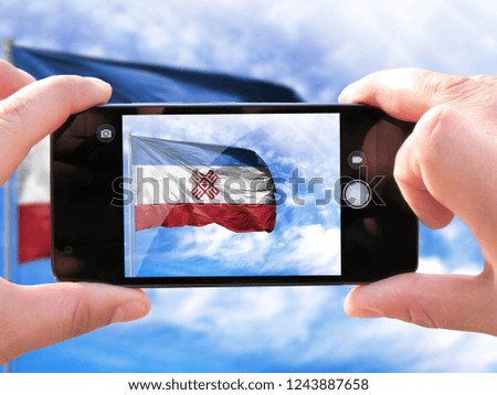 The hands of men make a phone photograph of the flag of Mari El