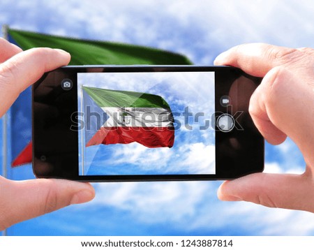 The hands of men make a phone photograph of the flag of Equatorial Guinea