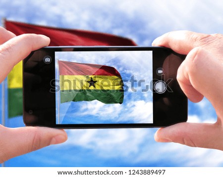 The hands of men make a phone photograph of the flag of Ghana