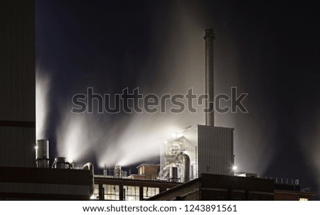A lot of steam on the roof of a power station building in the night.