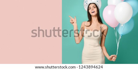 Amazed woman at russian traditional cap hat kokoshnik holding balloons over green background pointing to the free space. Looking at camera Expression. double background