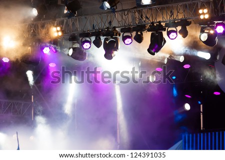 many spotlights that illuminate the stage at a concert with fog Royalty-Free Stock Photo #124391035