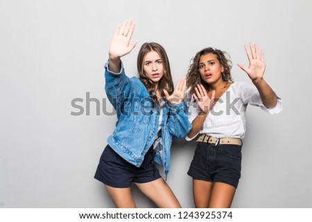 Two girls mixed race making stop sign isolated on gray background