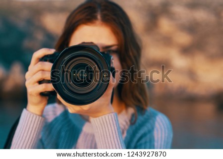 A woman with a camera near the face on the background of nature                       