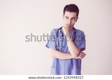 Pensive young male doctor touching chin. Medical decision concept. Isolated front view on white background.