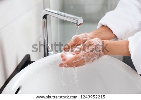 Woman washing hands with soap over sink in bathroom, closeup Royalty-Free Stock Photo #1243952215