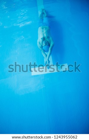 Photo on top of athlete man swimming on back of indoor pool
