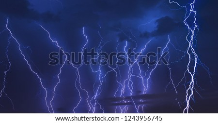 Thunder storm lightning strike on the dark cloudy sky background at night.