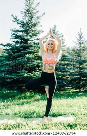 Photo of young curly-haired sports woman practicing yoga on rug 