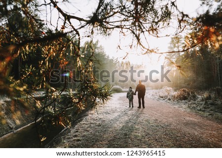 Father and son walk along the river bank. Silhouettes of people on the background of nature. Winter Christmas landscape. Winter forest on the river. Travel concept
