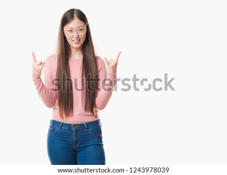 Young Chinese woman over isolated background wearing glasses shouting with crazy expression doing rock symbol with hands up. Music star. Heavy concept.