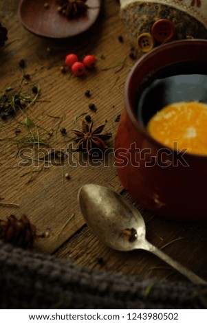 Details of still life in the living room home interior. Beautiful cup of tea with spices and sweaters on a wooden background. Cozy autumn-winter concept
