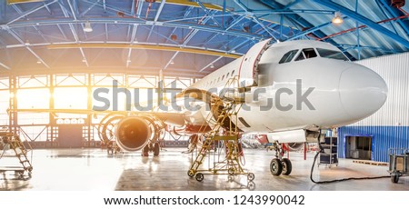 Maintenance and repair of aircraft in the aviation hangar of the airport, view of a wide panorama Royalty-Free Stock Photo #1243990042