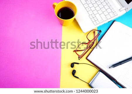 Top view of colorful working table have Headphones,laptop,mobile phone and cup of coffee on color blue,Yellow and pink background for create idea for business or design.Relax time,flat lay.
