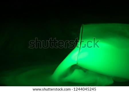 green smoke (evaporation) pour out of glass dishes on a black background