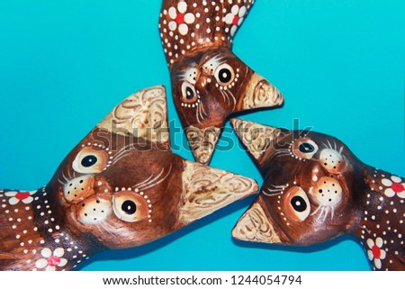  wooden brown cat souvenirs sit on a blue background
