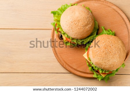 Two vegetarian burgers with fresh vegetables on rustic wooden table, top view. Healthy fast food background with copy space.