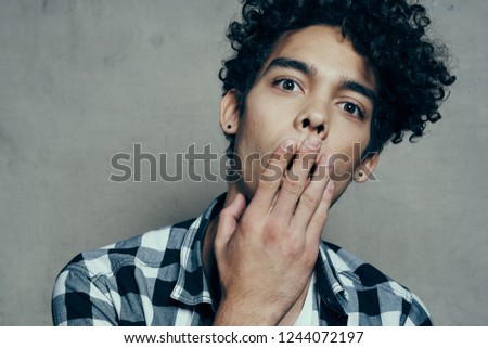 astonished curly man covered his mouth with his hand                               