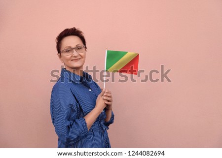 Congo flag. Business woman holding Congo flag. Nice portrait of middle aged lady 40 45 years old with a national flag over pink wall on the city street outdoors.