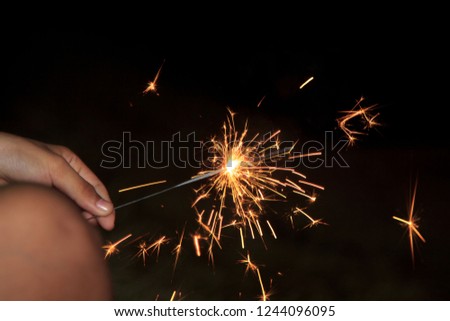 Fireworks light up the little girl's hand on a black background at night with Christmas celebrations around the world and festivals.