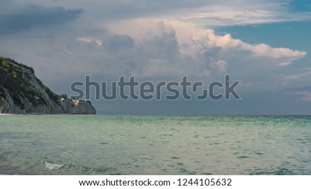 Beautiful seascape, green and turquoise tones and shades on flat sea water surface, blue sky grey pink clouds before storm at sunset time. Natural colorful pattern background. Byala rocks, Bulgaria.