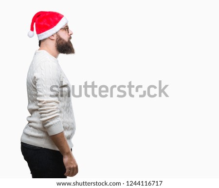 Young caucasian man wearing christmas hat and glasses over isolated background looking to side, relax profile pose with natural face with confident smile.