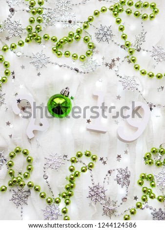 Christmas and New Year background with numbers 2019, silver and green decorations and light bulbs.