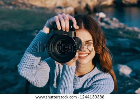 A happy woman in nature holds a camera in front of her eyes                      