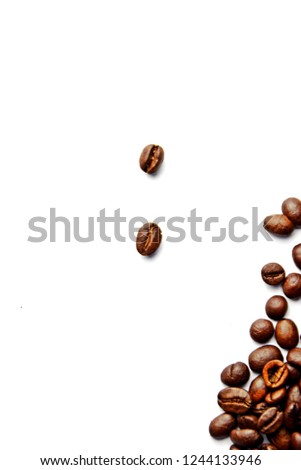 Coffee beans lie on a white surface and protrude into the picture - white background with coffee beans on it and space for text or other elements
